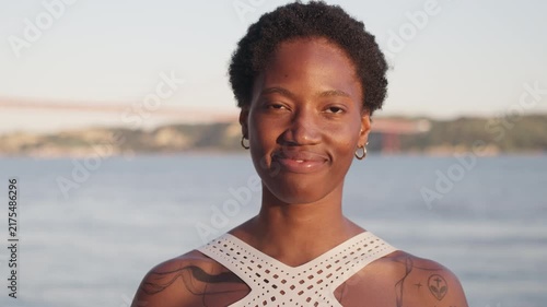 Close-up portrait of a smiling Black African American woman after an outdoor workout by the waterfront.