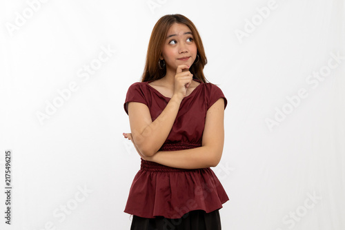 Obraz na plátne Thoughtful Young Woman With Long Hair Pondering In Maroon Top Against Plain Whit