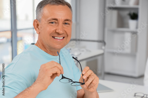 Healthy aging and vision care, mature man holding eyeglasses with a confident...
