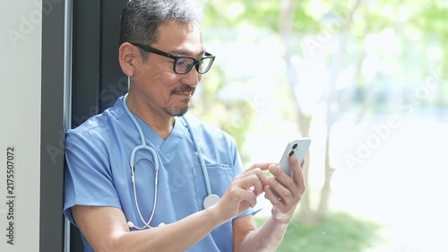 病院でスマートフォンを使う中高年の医師