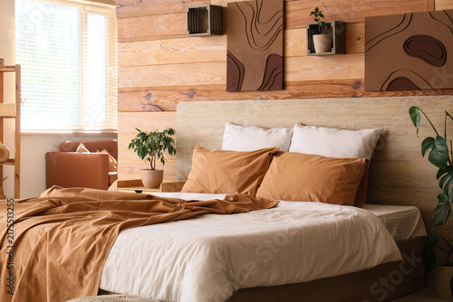Fotografie Interior of stylish bedroom with comfortable bed, bedside table and houseplant