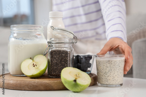 Foto Young woman with chia seed yogurt and fruits on table at home, closeup