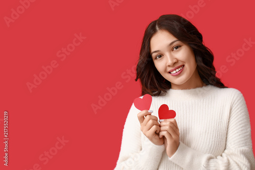 Canvastavla Beautiful young Asian woman with red paper hearts on color background