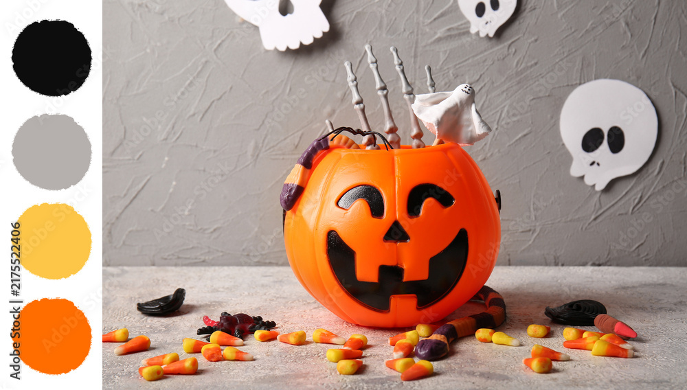 Obraz premium Halloween celebration and trick or treat tradition, plastic pumpkin bucket filled with candy and spooky decorations on a textured gray background