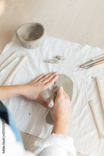 Women artist pottery shaping clay on a worktable with tools and cloth in a top-down perspective, focused and creative activity in crafting and production of handmade ceramics
