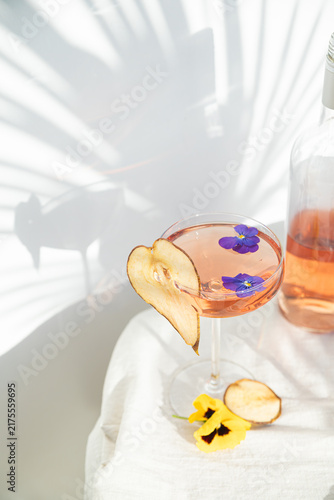 Two rose wine glasses with summer cocktails with leaves shadow. Tropical light top view background with palm shadow