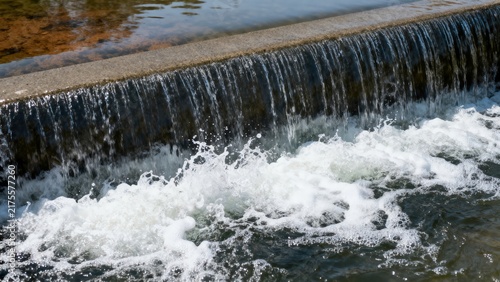 Concrete Weir Waterfall With Cascading Flow and Splashing White Foam in River