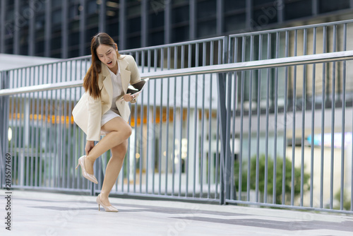 фотографія Asian businesswoman suffering ankle pain while walking in high heel outdoor, Foot injury, discomfort, workplace stress, mobility problem, accident, health risk during to office