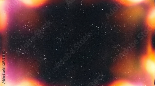 Vintage film texture showing vibrant orange and pink light leaks around a dark grainy frame. Film texture adds a nostalgic analog aesthetic with dust and scratch details for cinematic overlay.