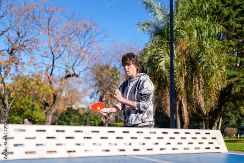 Young man playing ping pong outdoors in park