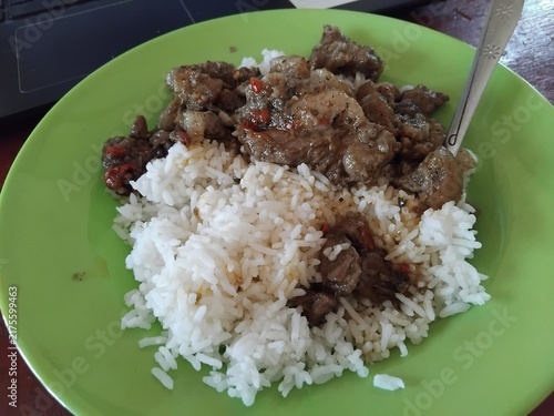 Bild auf Leinwand Plate of white rice with savory beef stir-fry and chili, served on green plate