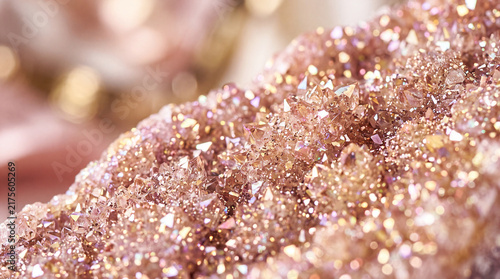 Macro close-up of a sparkling pink quartz crystal druse geode with shimmering rose gold metallic textures and beautiful soft bokeh background.