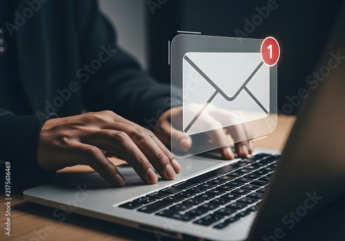 Person typing on a laptop with an email notification icon appearing, representing digital communication