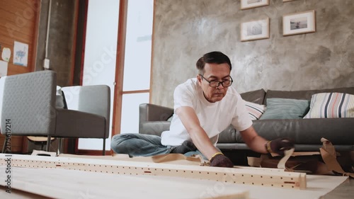 One Asian mature man unpacking flat-pack furniture cardboard, preparing DIY tools for self-assembly in living room, home improvement, wooden craft install hobby workshop, handyman active lifestyle.