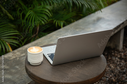 A freelancer enjoys coffee while working on a laptop outdoors