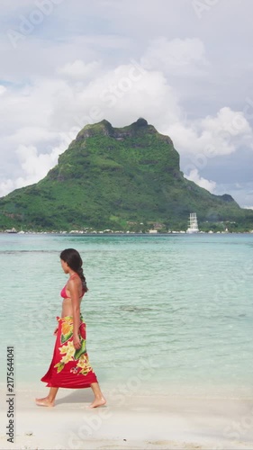 French Polynesia Vacation Travel woman walking on paradise motu beach on holidays on Bora Bora with Mount Otemanu. Girl in pareo in Tahiti, French Polynesia. Raw video of real woman without makeup