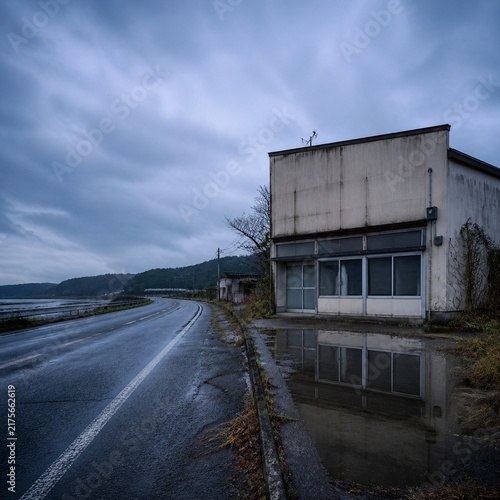 Square roadside view of an abandoned Japanese building after rain