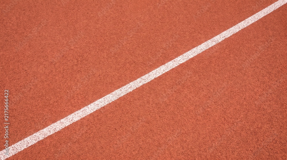 Naklejka premium White lane marker on a textured red running track surface