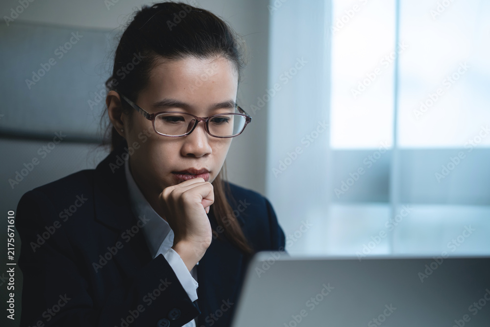 Fototapeta premium Businessman Working on Laptop at Modern Office Desk While Showing Signs of Stress, Fatigue and Difficulty Managing Work Tasks