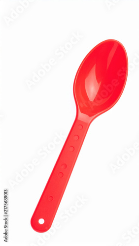 Red plastic spoon with long handle, isolated on white background, showing simple household utensil with clean contours and bright color