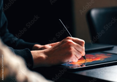 Economy creator concept. Person using stylus on tablet to create digital art with vibrant colors in a focused, creative workspace.