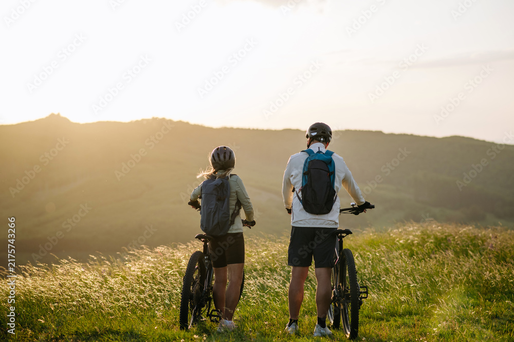 Obraz premium Senior couple at bike ride in nature, looking at sunset.