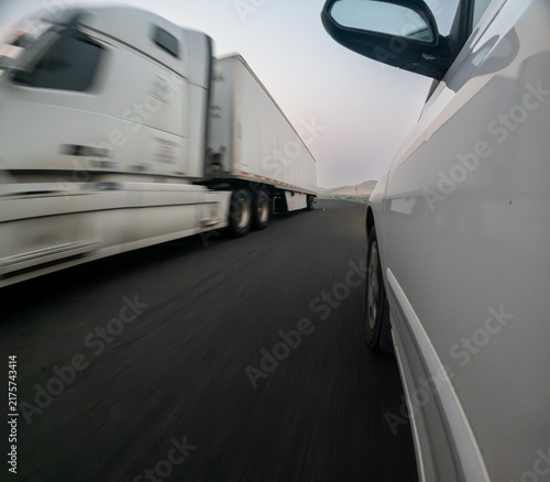 Highway scene showing a white semi-truck passing a car