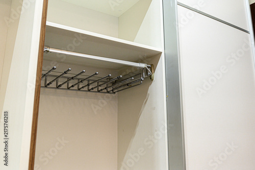Quadro su tela Interior of a compact built‑in wardrobe with a retractable metal clothes rail