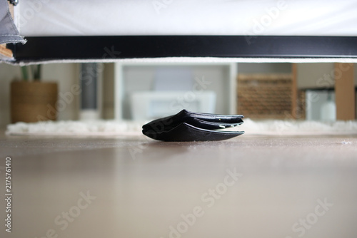 Cuadro en lienzo Wallet placed on the floor under a bed in a room