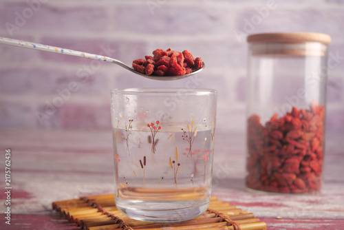 Fotografie Goji berries on spoon above glass water