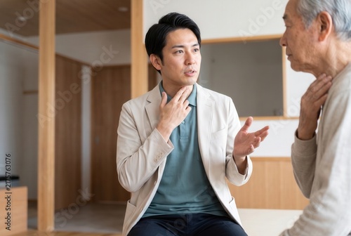 Young male speech therapist explaining to a senior man about throat problems during a consultation