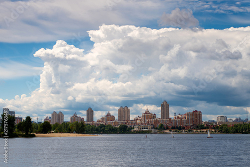 Cuadro en lienzo Panoramic view of Kyiv's Obolon district across the Dnipro River, with residential buildings, sailboats and dramatic summer clouds