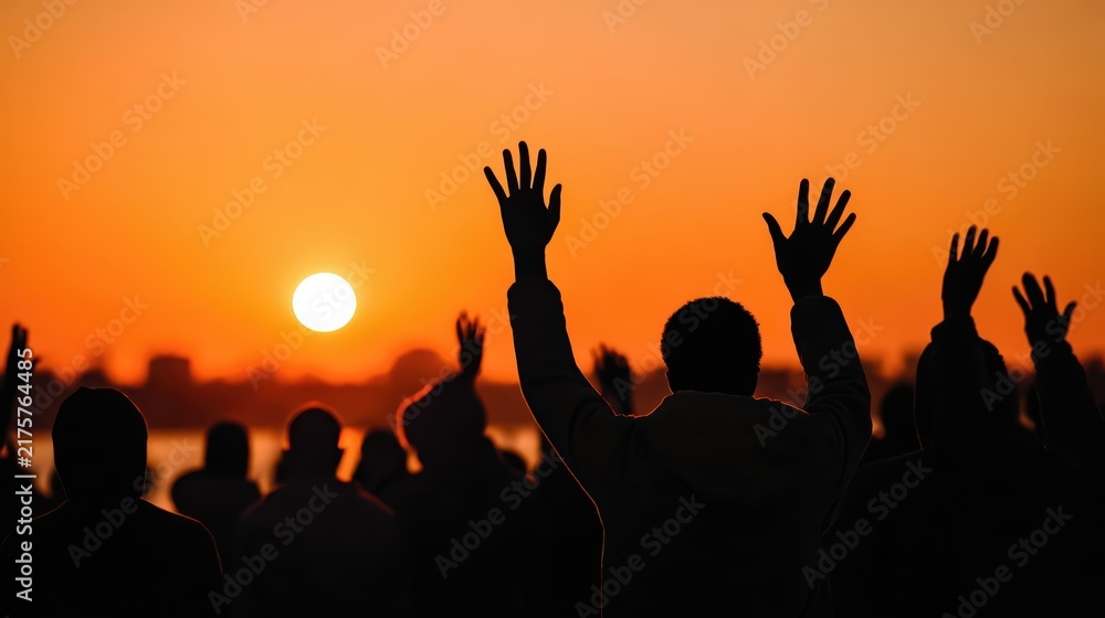 Fototapeta premium Dramatic silhouettes of a protest crowd raise their hands at sunset. Glowing orange sky and strong backlighting evoke unity, resistance, and activism.