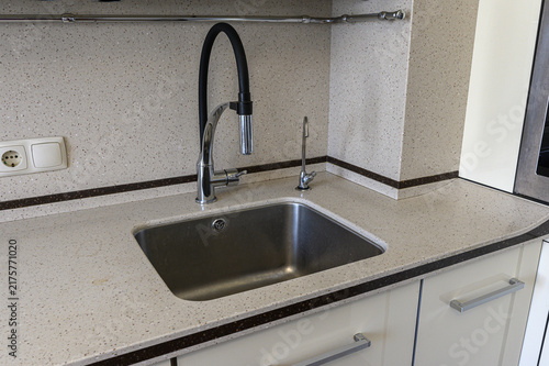 Fotografie stainless steel sink is set into speckled beige artificial stone countertop