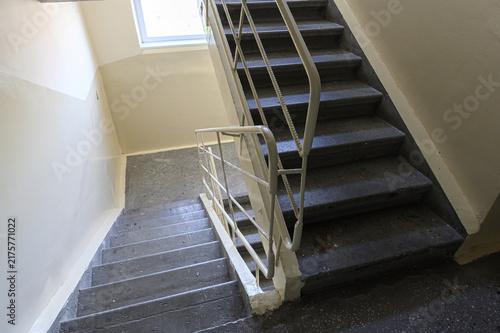 Bild auf Leinwand utilitarian staircase in residential entryway features dark concrete steps, white metal handrail