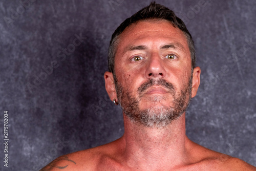 Featured portrait of a man with a serious expression, the man is forty-two years old, with short hair, a beard, light eyes and a sun-tanned face