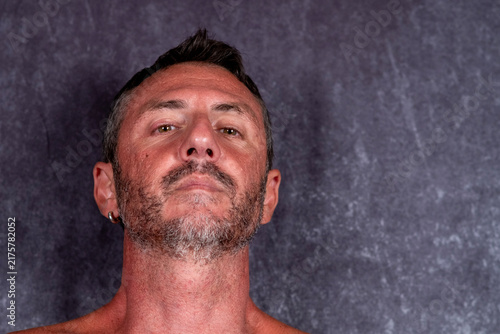 Featured portrait of a man with a serious expression, the man is forty-two years old, with short hair, a beard, light eyes and a sun-tanned face
