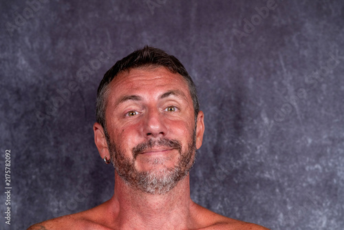 Featured portrait of a man with a smiling expression, the man is forty-two years old, with short hair, a beard, light eyes and a sun-tanned face