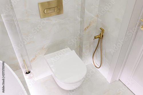 Quadro su tela modern bathroom features wall‑mounted white toilet, gold flush plate, brass bide