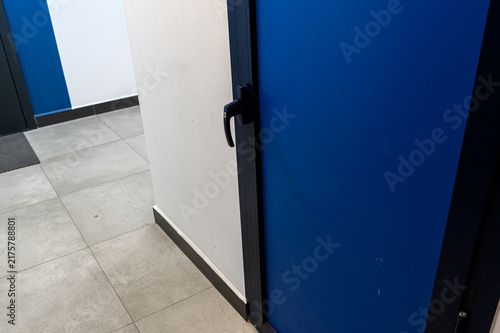 Obraz na płótnie modern blue metal door with black lever handle is set in white wall with black baseboard