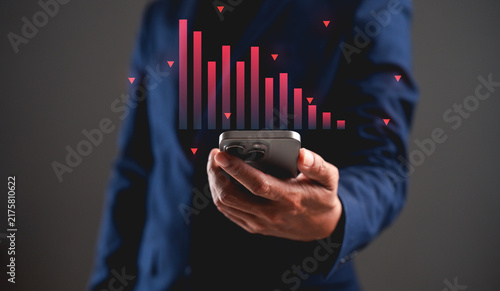 Person in suit holding smartphone with digital red bar graph overlay, symbolizing financial decline or data analysis