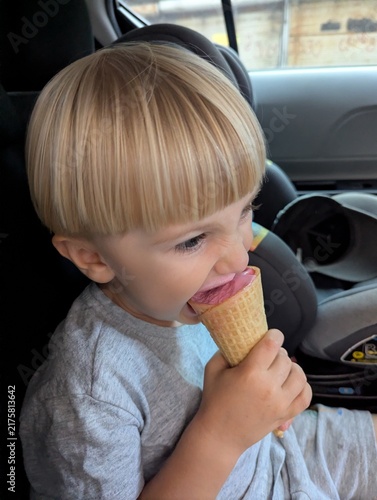 Little boy in the car, eating ice cream to stay cool during a heatwave. Hot summer day, simple pleasures. Classic way to beat the heat.

