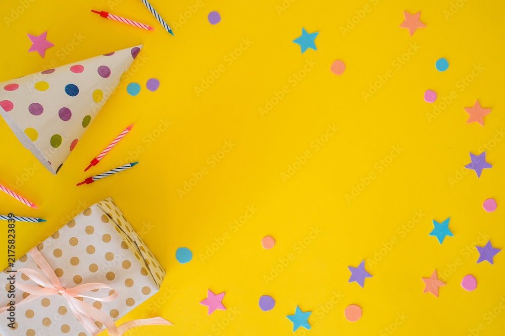 Fototapeta premium Birthday banner with a party hat, festive candles, and a gift on a yellow background with space for text