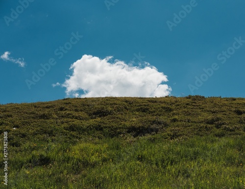 Large White Cloud in Blue Sky Over Green Hill