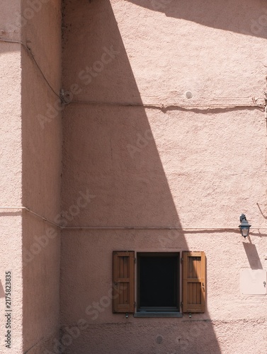 Pink Stucco Wall with Small Shuttered Window in Shadow