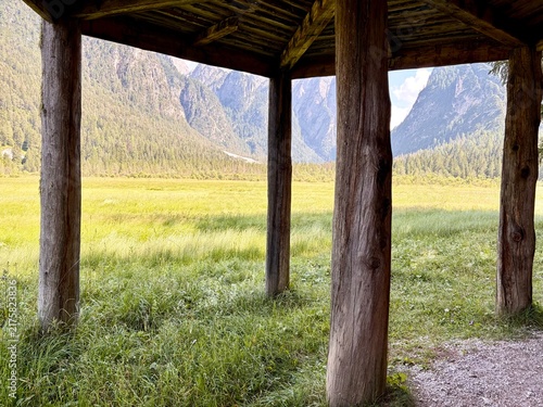View Through Wooden Pergola to Green Meadow and Mountains