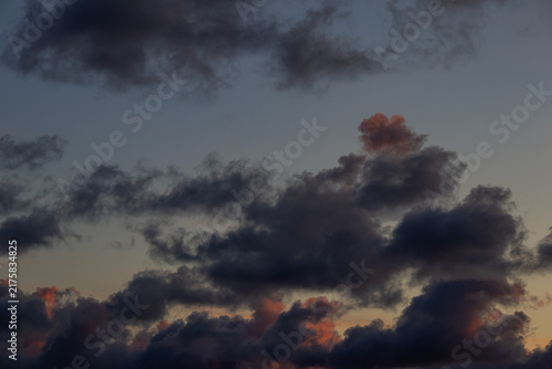 Bild auf Leinwand Atmospheric cloudscape showing dark cumulus clouds catching pink and orange sunl