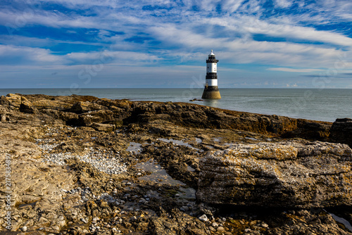 Cuadro en lienzo Trwyn Du Lighthouse standing offshore beyond rocky foreshore at Penmon Point on