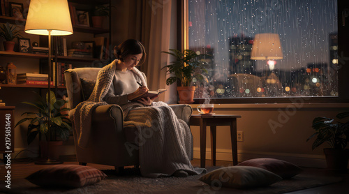 Woman writing in journal during rainy night at home