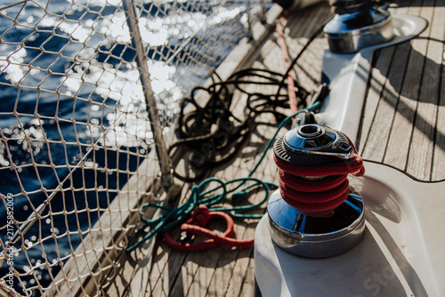 Red rope on a winch on the wooden deck of a sailboat at sea